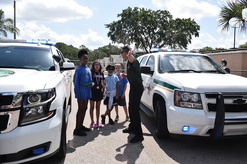 Fifth graders Tamea Gibson, Anna Dorin, Jaidon Chhith and Brady Colcu listen as Deputy Tom Kaczmark explains why it's important to know their location so they can inform first responders when they arrive on a scene.