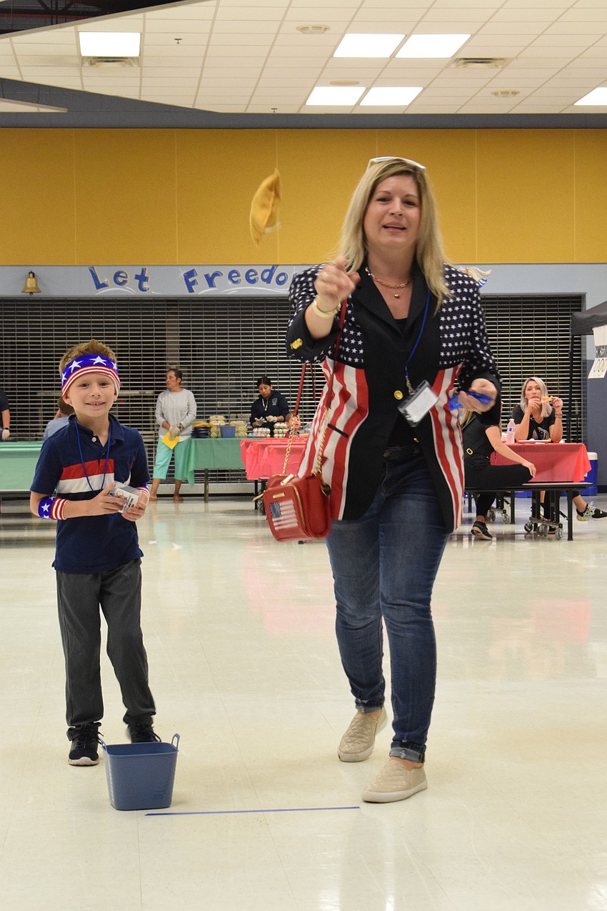 Luca Montovani, a first grader, cheers as his mother, Melissa Montovani, throws a bag at a set of bowling pins to knock down as many as possible.