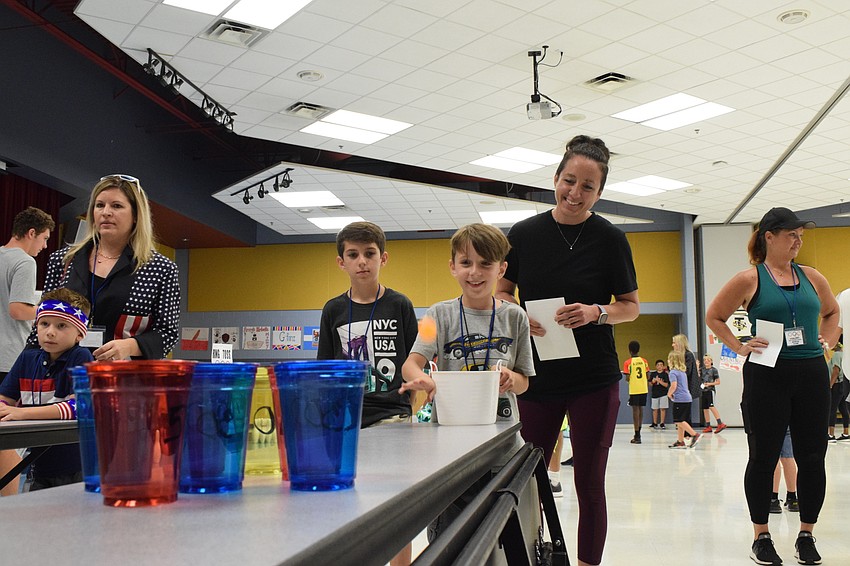 Dylan Kiefer, a sixth grader at Braden River Middle School, watches his brother, Carson Kiefer, who is in sixth grade, try his hand at a game of ping pong while their mother, Kelly Kiefer, cheers for them.