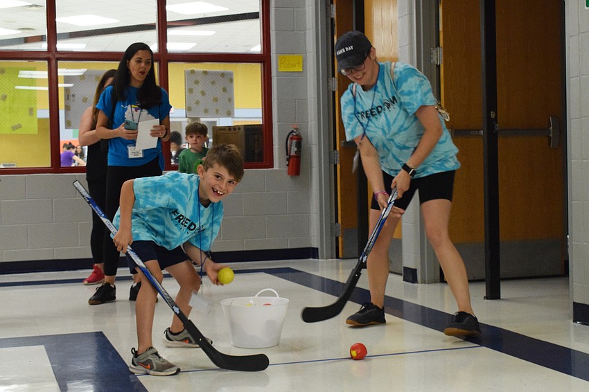 Second grader Abel Hilliard and his mother, Megan Hilliard, try to score as many balls in the net as possible during a game of hockey. 