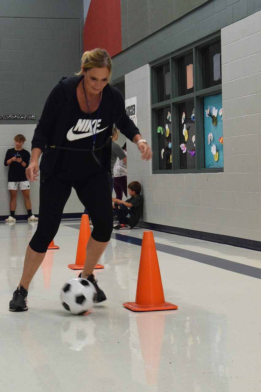 Allison Wyman dribbles the ball around the cones to her son Dane Wyman, who is in second grade, so he can dribble the ball back.