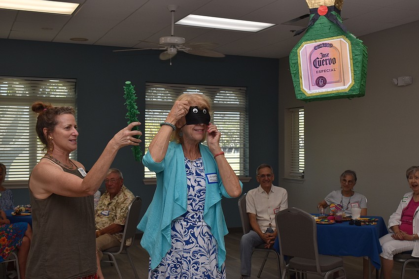 Suzy Brenner arms Angela Bennink for the piñata.