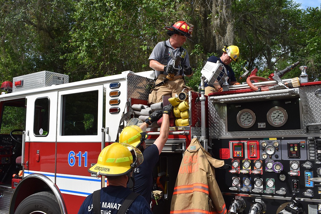 Lieutenant Shawn Battick helps the team load the firehose onto the truck after a training exercise.