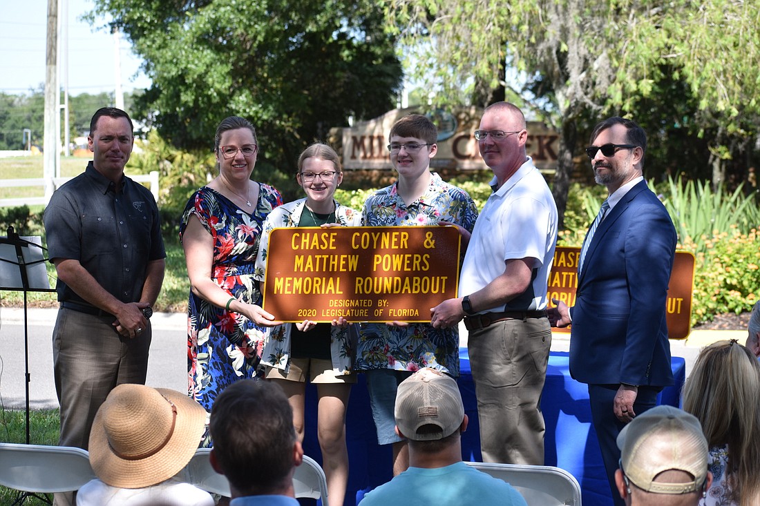 Florida Representative Tommy Gregory presents Rebecca, Katie, Robert, and Dan Powers with a plaque, alongside Andy Orrell of the FDOT.