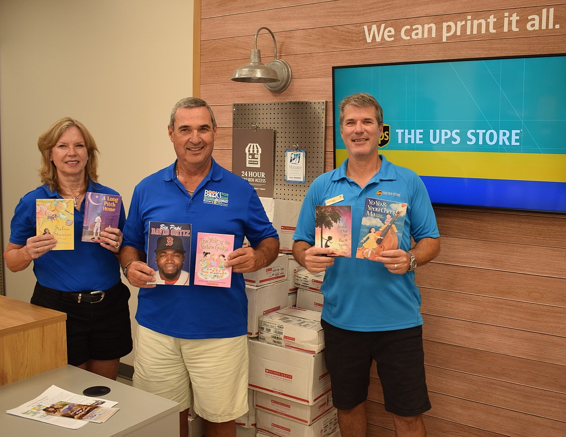 JoAnn Shakon and Jim Wingert of the Rotary Club of Lakewood Ranch join with Mike Hornyak of The UPS Store  to show off donated books.