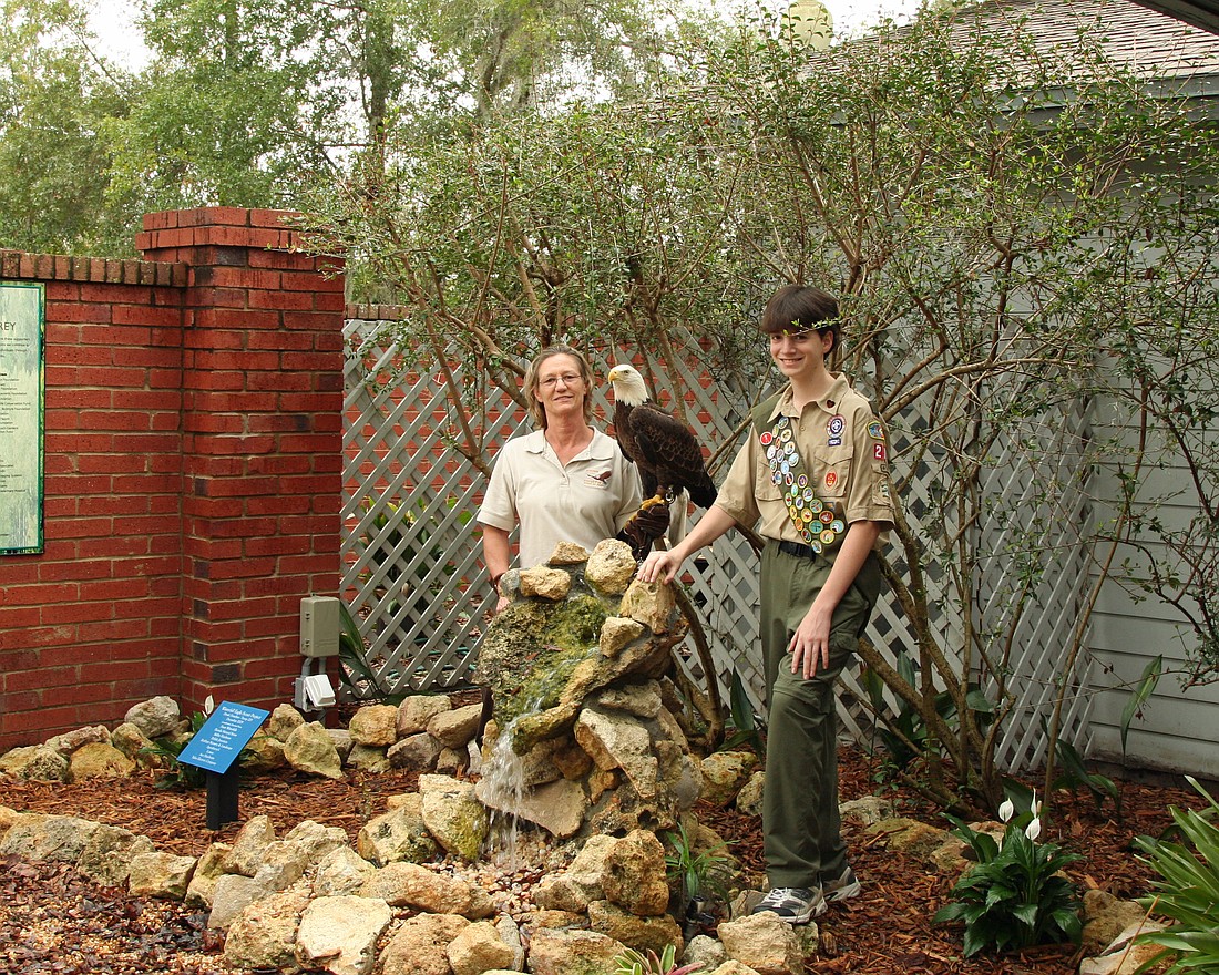Newly named Eagle Scout Derek Donahue of Maitland, right, and Dianna Flynt of the Audubon Center for Birds of Prey pose with the rock feature Donahue's team built. Donahue is 13 and is a member of Boy Scout Troop 205 of the First Presbyterian Church.