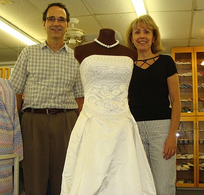 Photo by: Kristy Vickery - Sewing Studio owners Pat and Mark Sauer stand next to Kim McGauley's handmade wedding dress displayed in the store.