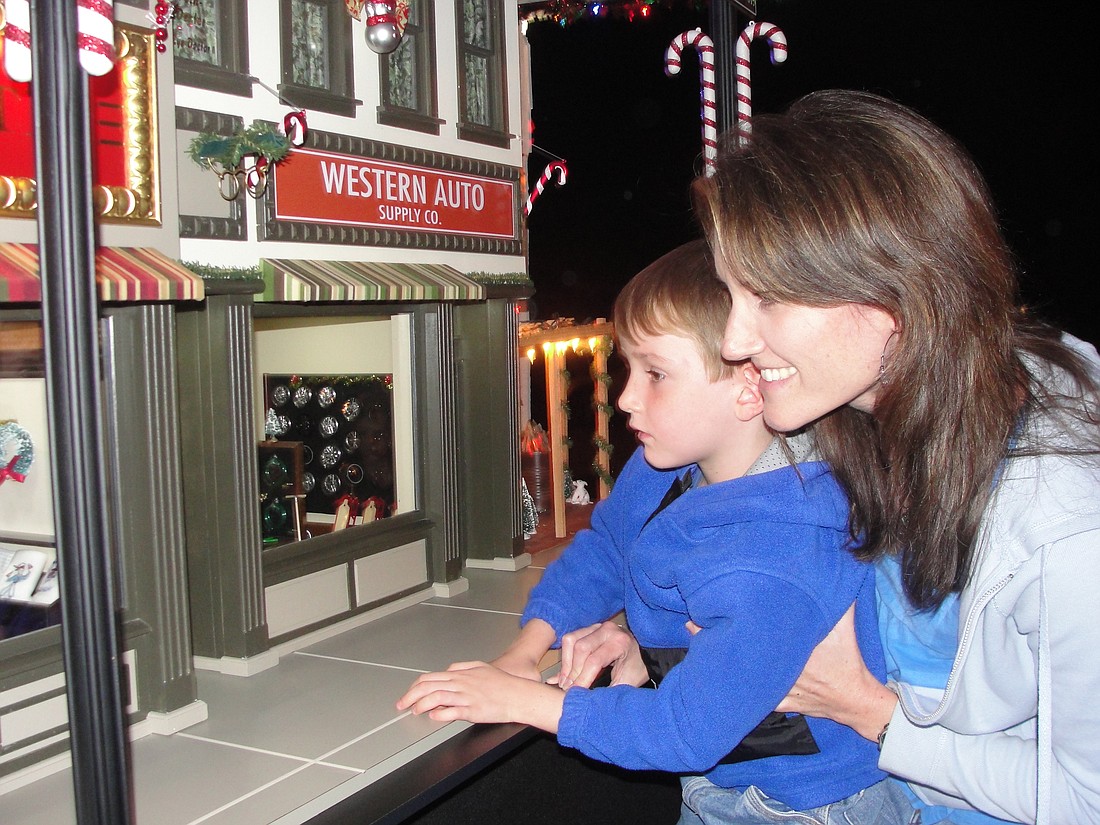 Photo by: Kerri Anne Renzulli - Brenda Bartelt lifted her son Mason up to peer into one of the shop's windows. Akers built the village based on his childhood town in Ohio.