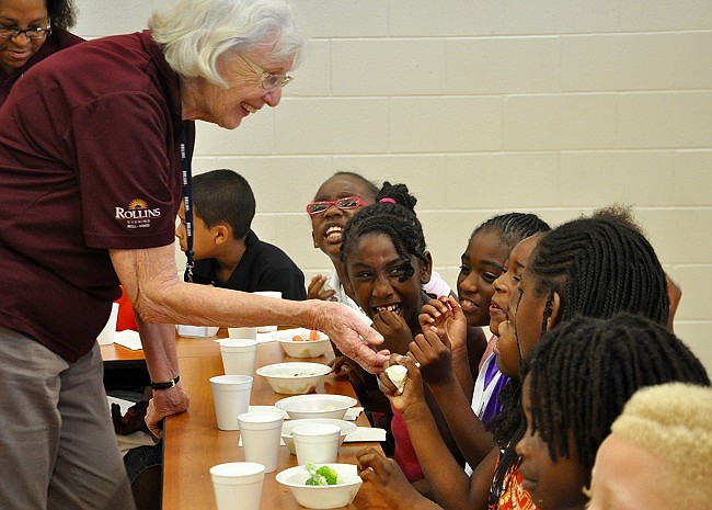 Photo by: Anne Lottman - Volunteer Barbara Reuter passes out nutritional snacks to students as part of the Catch Healthy Habits program.