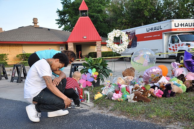 Photo by: Tim Freed - Well-wishers pray for victims of a crash that killed a toddler and injured 13 other children on April 9. The driver who allegedly caused the wreck had a long criminal history.