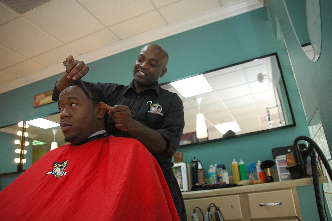 Photo by: Isaac Babcock - Supermen Fades to Fros co-owner Reggie Jones cuts longtime customer Phil Hastings' hair. Jones said he caters to all types of customers at his Hannibal Square location, just down the street from the posh Park Avenue corridor.