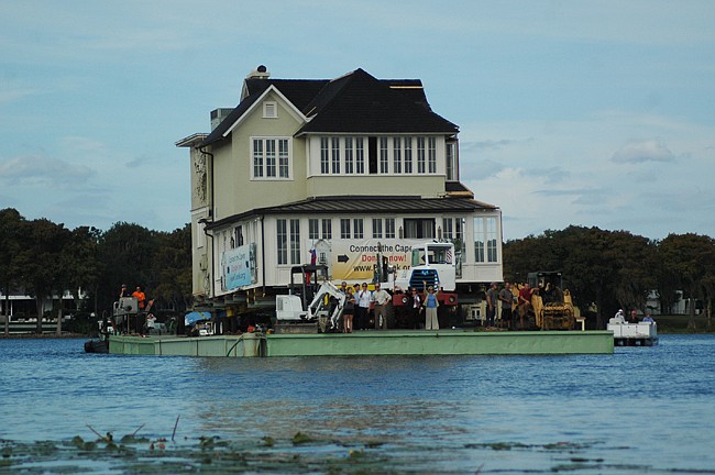 Photo by: Isaac Babcock - Preservation Capen organizers wave from their house boat as it floats across Lake Osceola Tuesday.