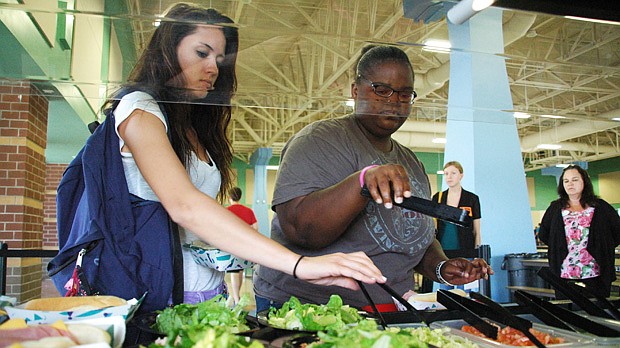 Photo by: Isaac Babcock - Oviedo High School students Cassandra Vivian, left, and JoQwanda Sykes peruse a school salad bar, part of the school's attempts to get kids interested in healthy habits.