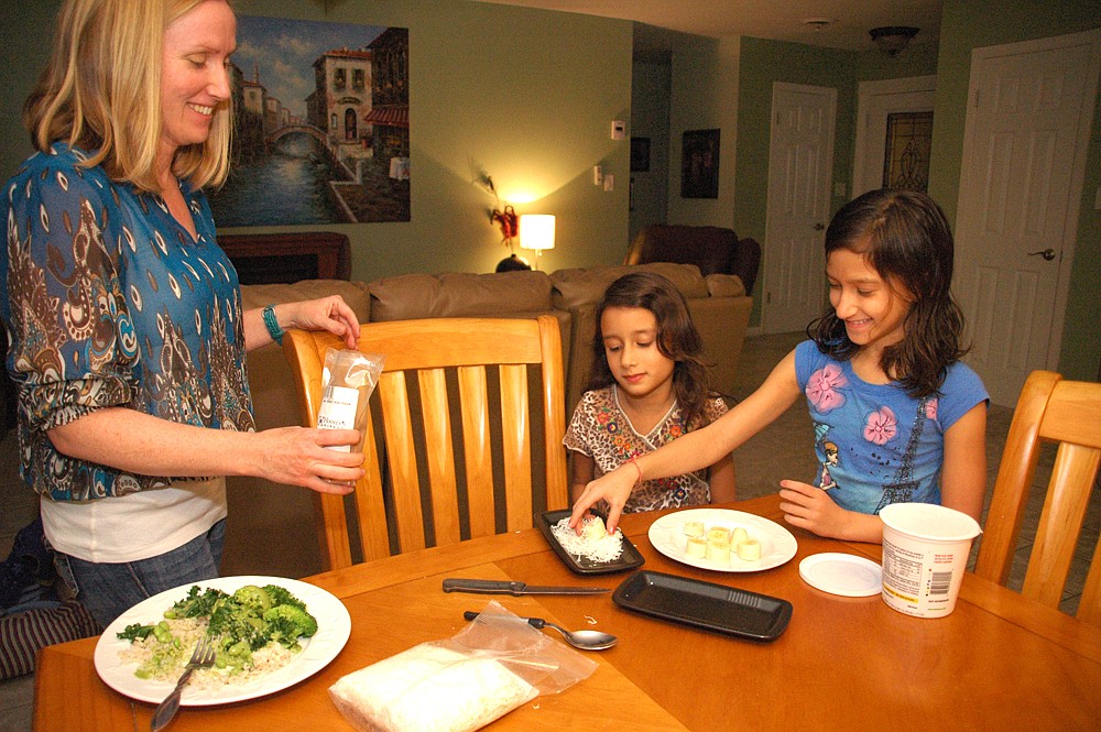 Photo by: Isaac Babcock - Gretchen Goel and daughters Ksenia and Anika prepare a vegan meal with some foods they've grown from their own garden.