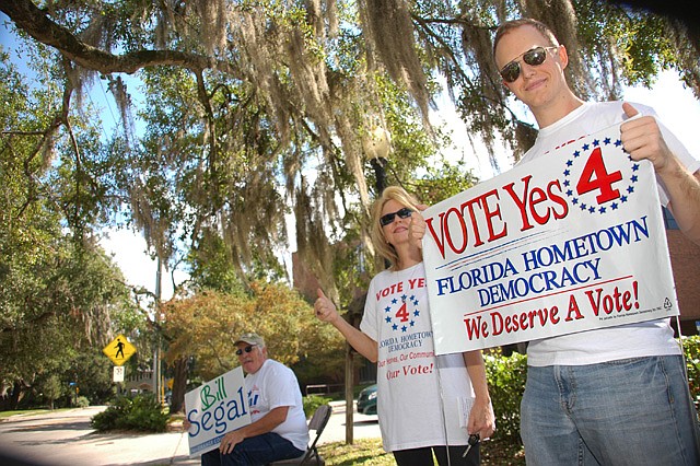 Photo by: Isaac Babcock - Supporters of Amendment 4 wave signs near the Winter Park Library Thursday morning as voters arrived for early voting.