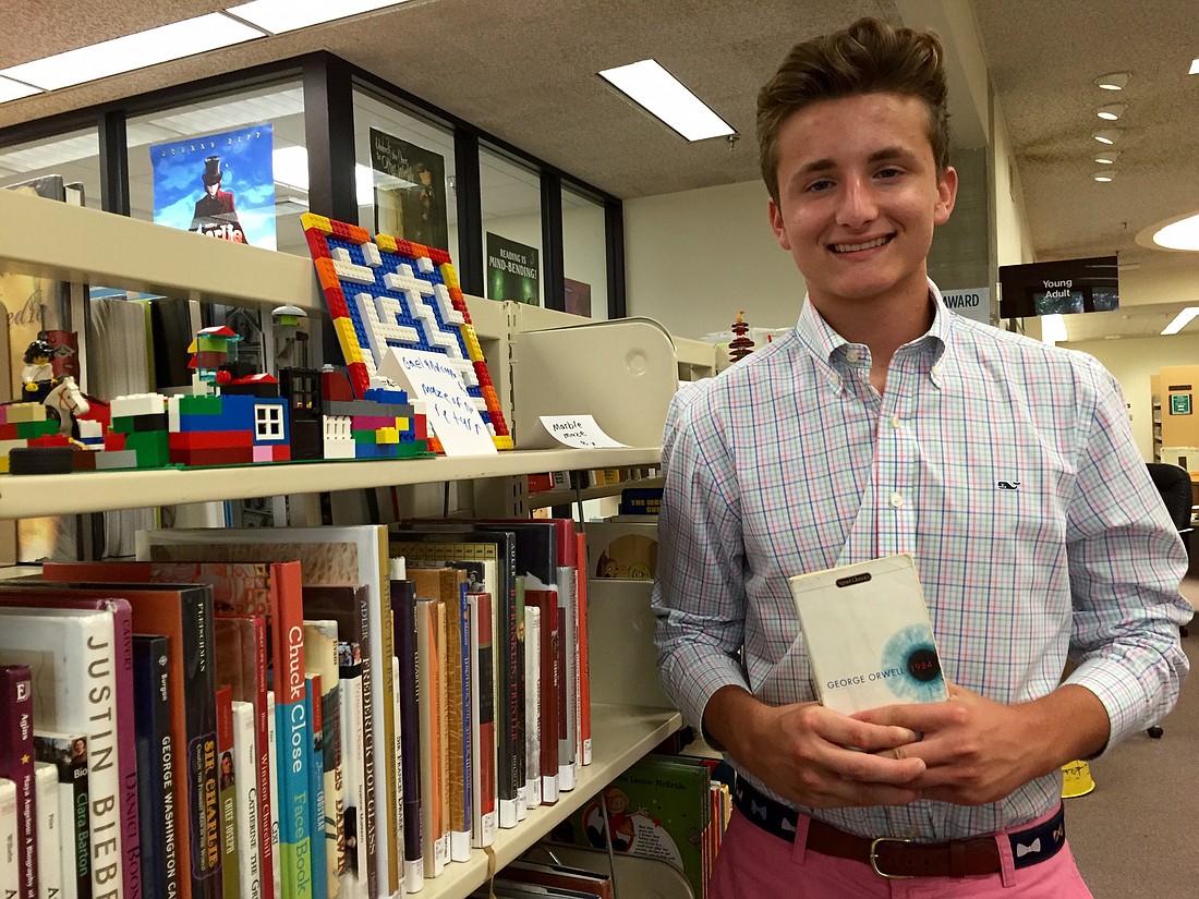 Photo by: Ciara Varone - Joey Cocchiarella picks up a copy of George Orwell's 1984, which he's reading for school, at the Winter Park Public Library.