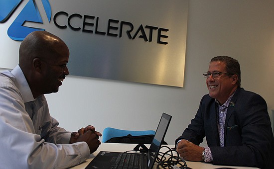 Photo by: Sarah Wilson - Accelerate analyst Brian Moseley, left, assists small-business owners such as Jeff Campese, right, with their banking and loan needs at the new Accelerate office in Hannibal Square.