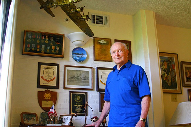 Photo by: Allison Olcsvay - Sandy Gonzalez stands with tokens of his past, mementos and awards from his time at war.
