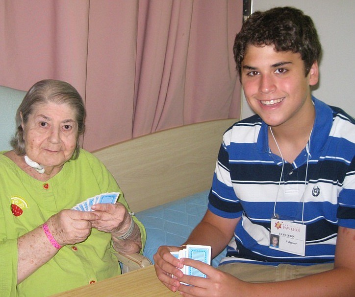 Photo courtesy of the Jewish Pavilion - Evan, a Jewish Pavilion volunteer, plays cards with Pearl Schiffer, the author's mother. The author praises the Jewish Pavilion for its services to the elderly.