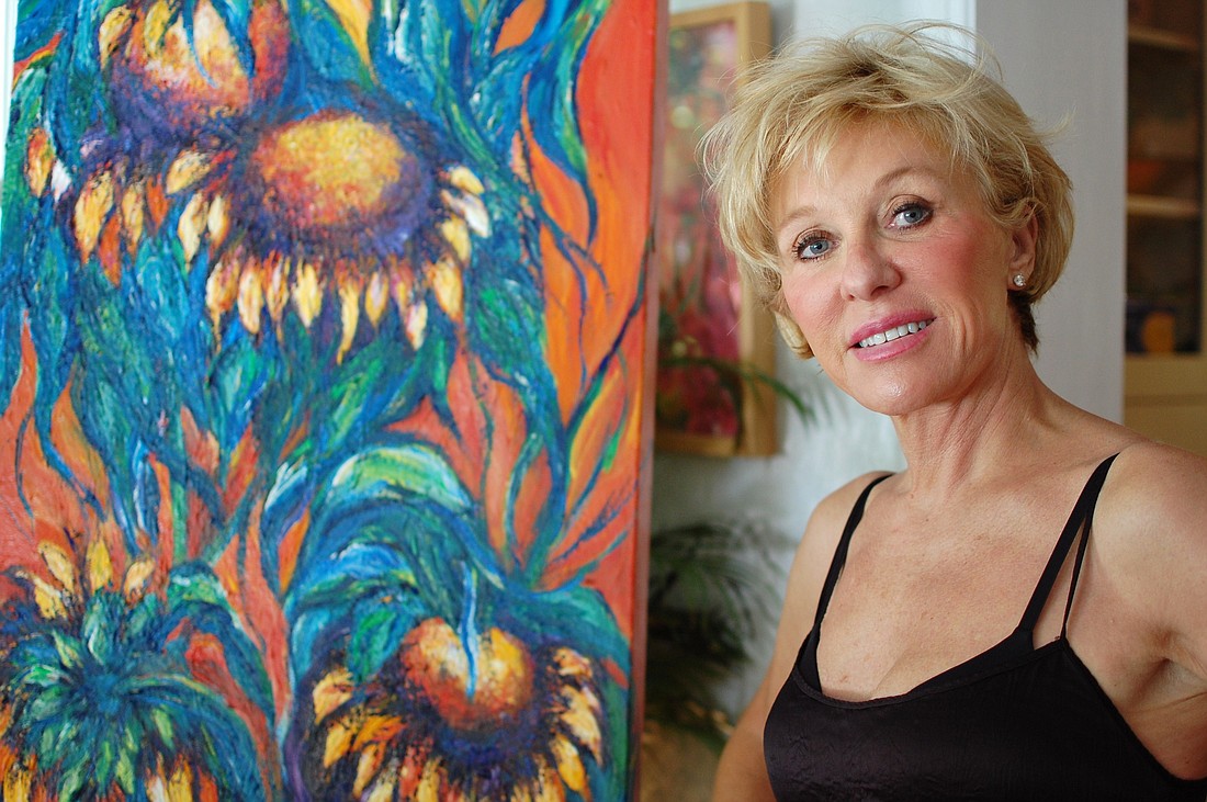 Photo by: Tina Russell - Winter Park artist Marcia Lain Herring shows off one of her sunflower paintings.