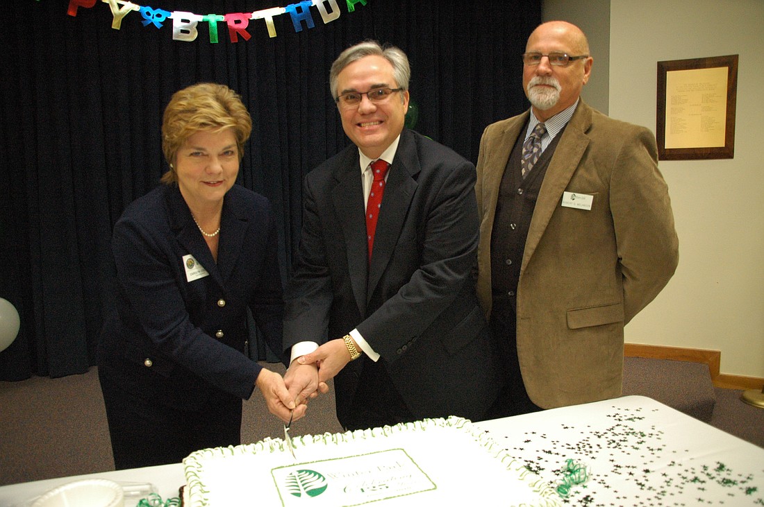 Photo by: Isaac Babcock - Winter Park City Commissioner Carolyn Cooper, far left, and Mayor Ken Bradley, center, helped cut the cake with Library Director Bob Melanson, right.