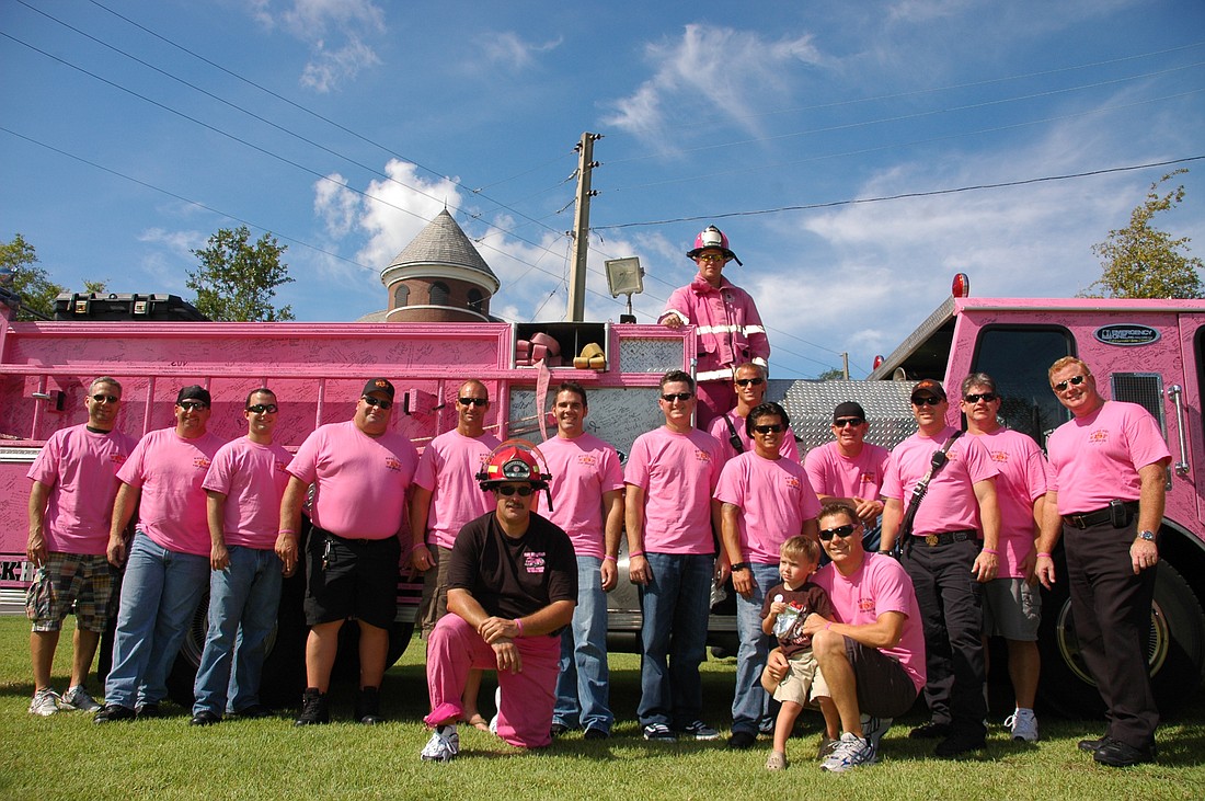 Photo by: Isaac Babcock - Firefighters from across the country pose in front of a pink fire truck in Winter Park's Central Park on Friday as a part of the Pink Heals campaign, which raises money and travels the country to visit cancer patients and rai...
