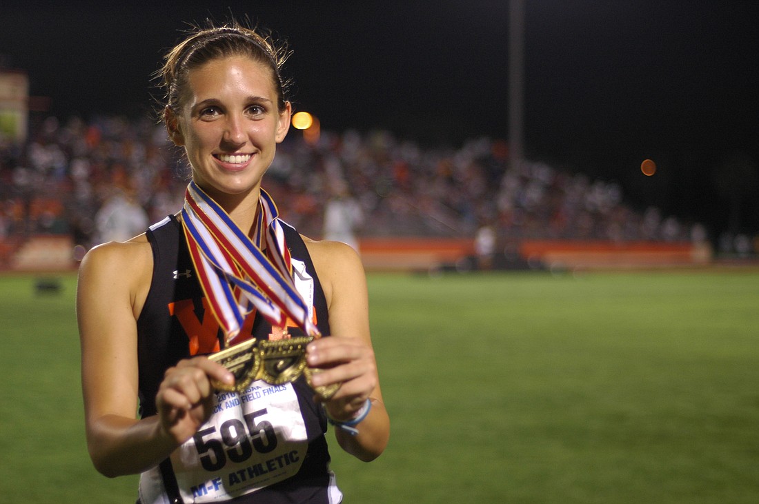 Photo by: Isaac Babcock - All smiles with three medals in her hands, Winter Park's Shelby Hayes stands on Showalter Field after doing something no class 4A runner has done before.