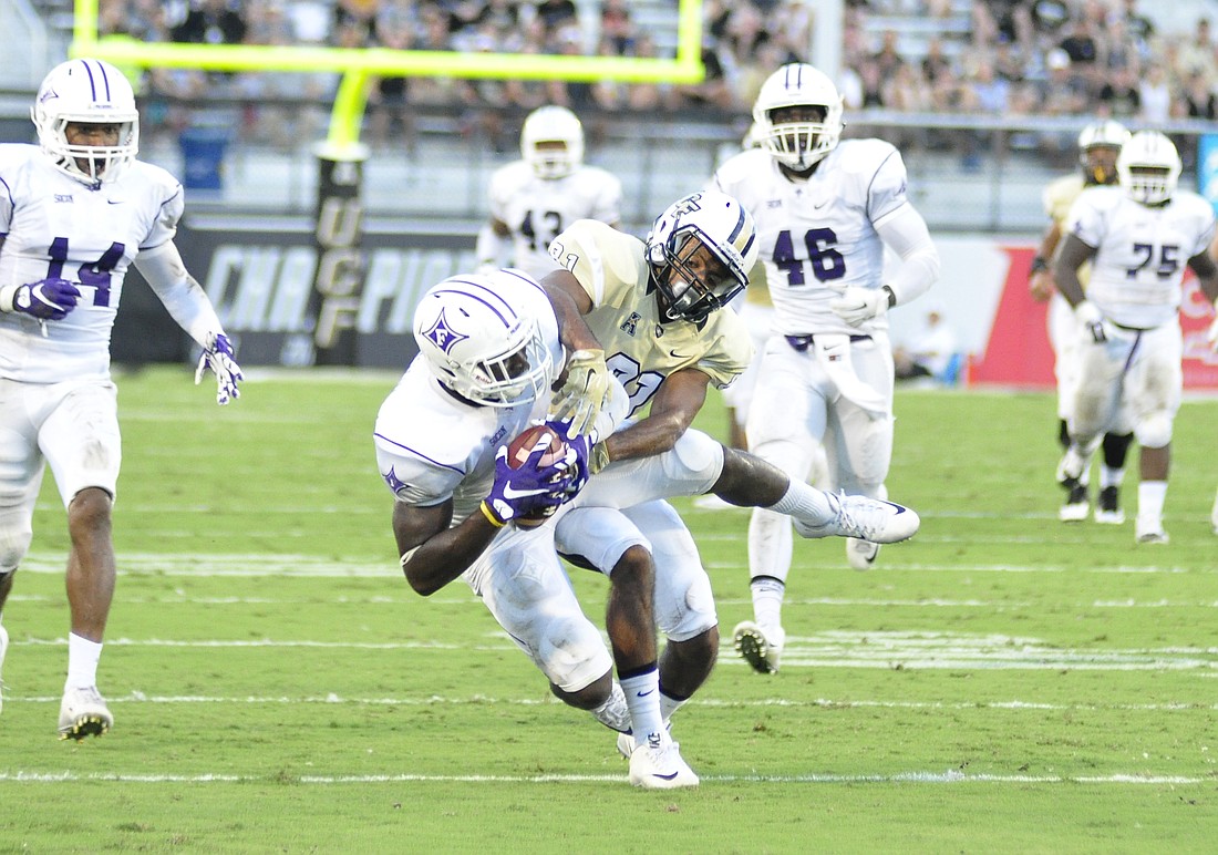 Photo by: Isaac Babcock - UCF wide receiver Chris Johnson tries to stop Furman's Trey Robinson from intercepting a pass Saturday during UCF's first loss to an FCS team since joining the NCAA FBS in 1996.