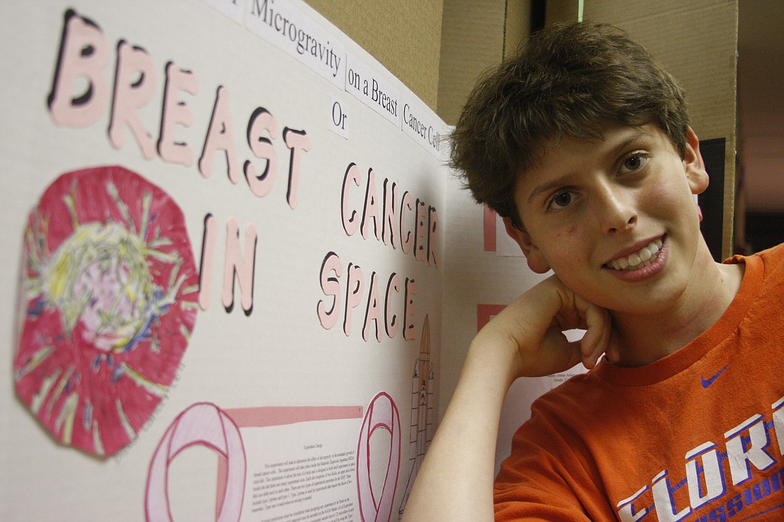 Photo by: By Katie Dees - Baron Hahn, an eighth-grader at Maitland Middle, stands with his group's proposal on the affects of microgravity on breast cancer cells.