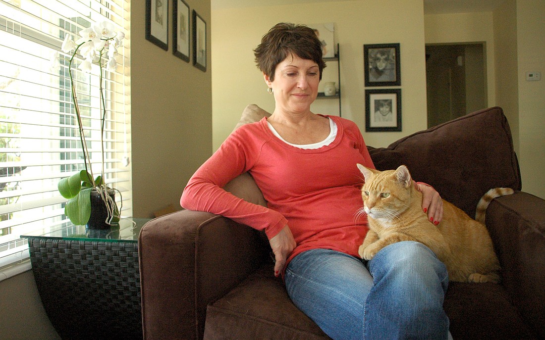 Photo by: Isaac Babcock - Laura Hansen sits in her Winter Park home with her cat, Gary, who was found three months after disappearing thanks to a local website that connects owners with people who find lost pets.