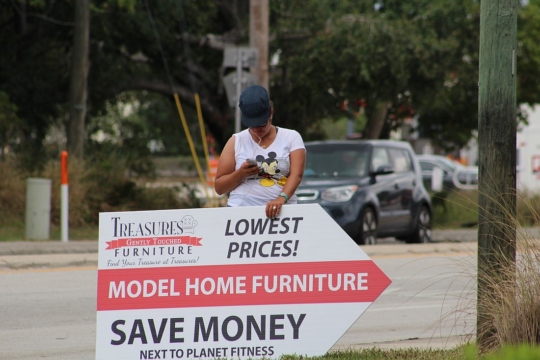 A sign spinner holds a sign on the sidewalk at the intersection of Maguire Road and West Colonial Drive. If passed, the ordinance will forbid human signs from being located on any city rights-of-way.