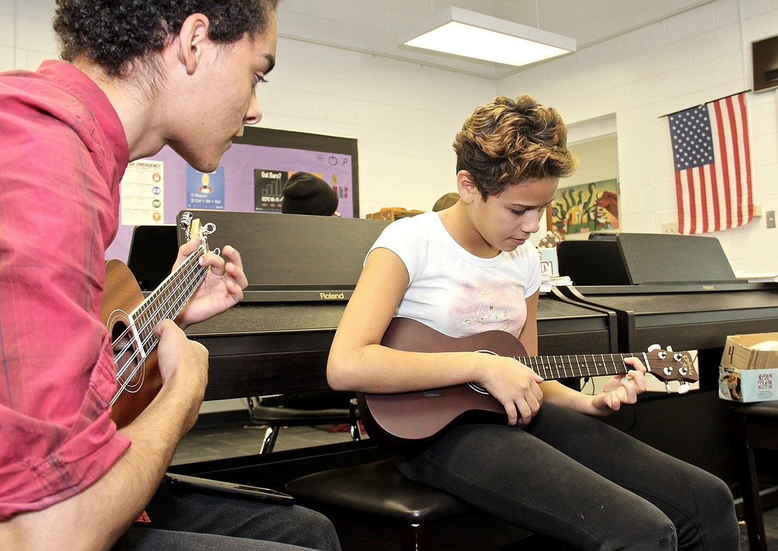 Orlando Guadalupe, left, helps teach a new student the basics of playing the ukulele.
