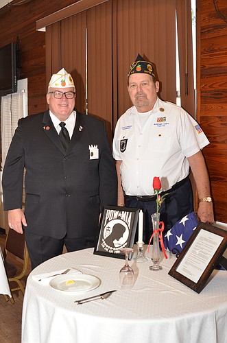 Florida State Commander Steve Shuga, left, and Post 63 Commander Judd Kuneman stand over the POW/MIA table, a symbol of the brothers who are unable to be with loved ones and family.