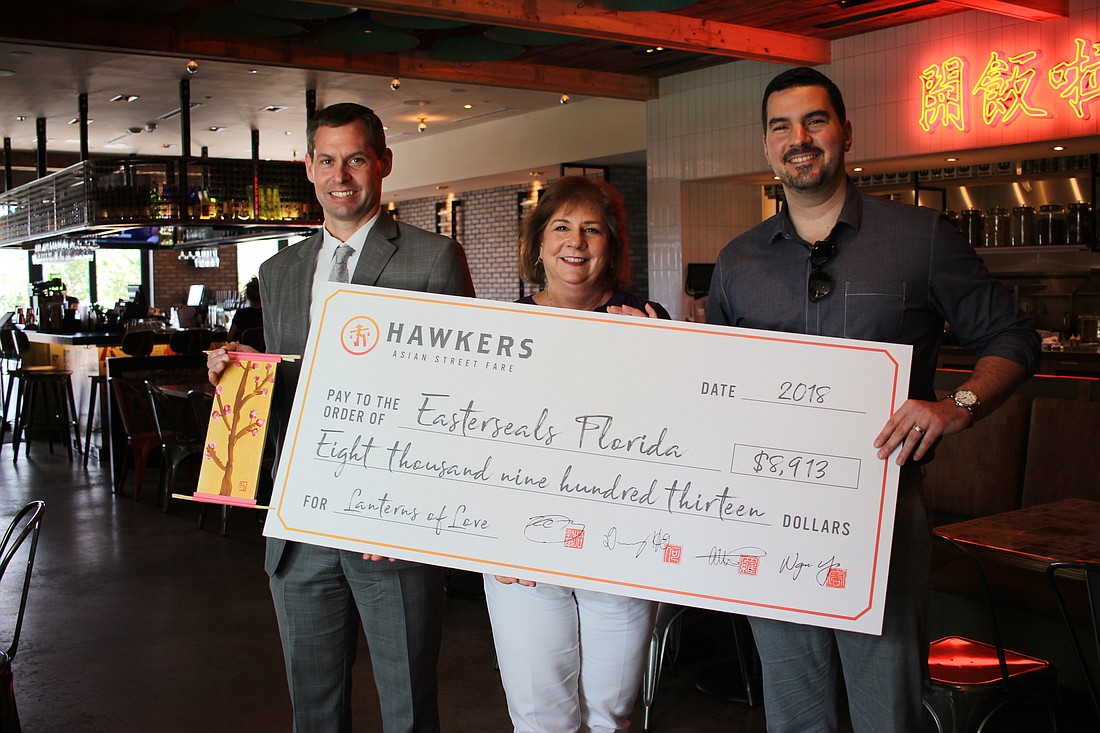 Hawkers co-owner and co-founder Kaleb Harrell, right, presented an $8,913 check to Sue Ventura, president and CEO of Easterseals Florida, and Jeff Lato, chief development officer of Easterseals Florida.
