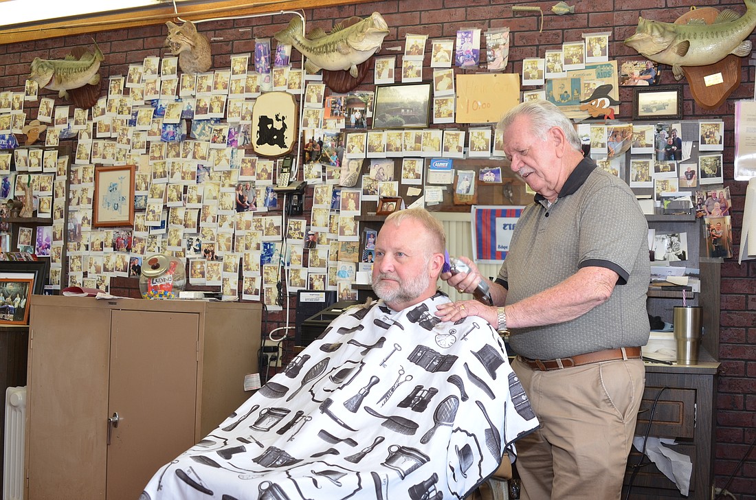 Larry Herrington engages all of his clients, including John Sills, seated, in conversation while he cuts their hair.