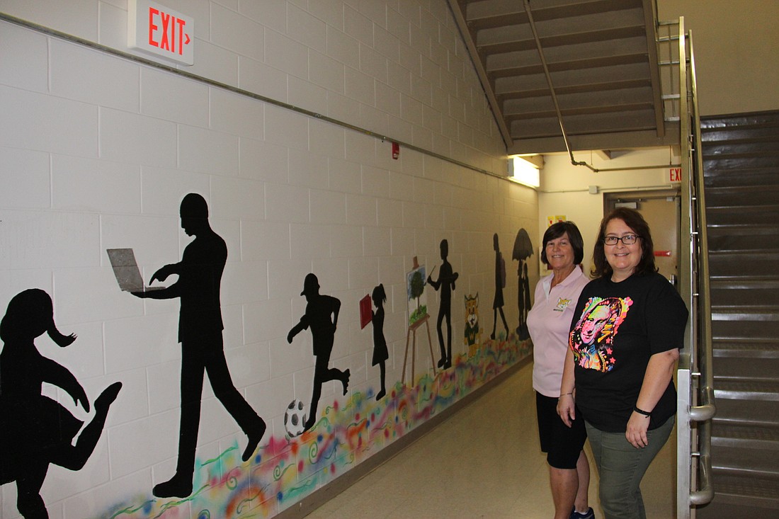 Whispering Oak art teachers Dana Christopher, left, and Vivian Alfonso proudly pose by the schoolâ€™s new mural.