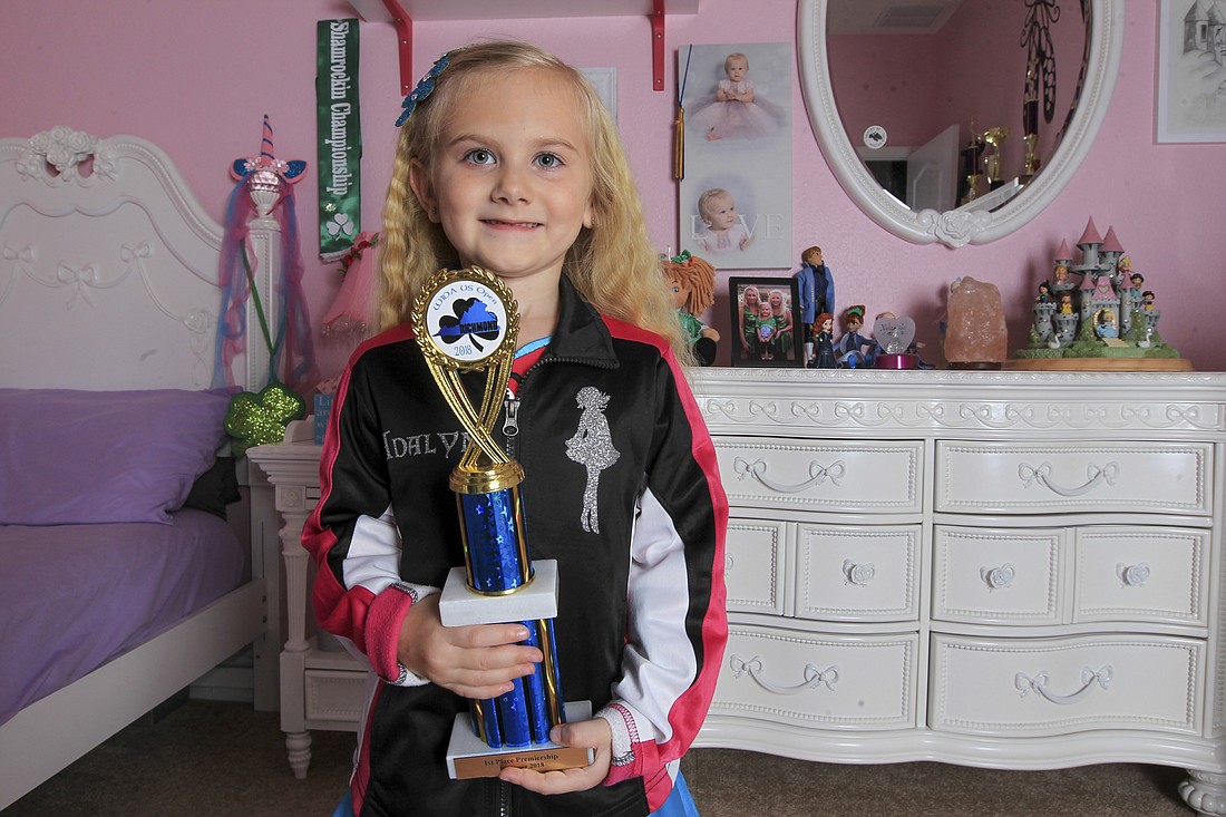 Adalyn Bradley proudly shows off the trophy she won from the World Irish Dance Associationâ€™s U.S. Open National Championships.