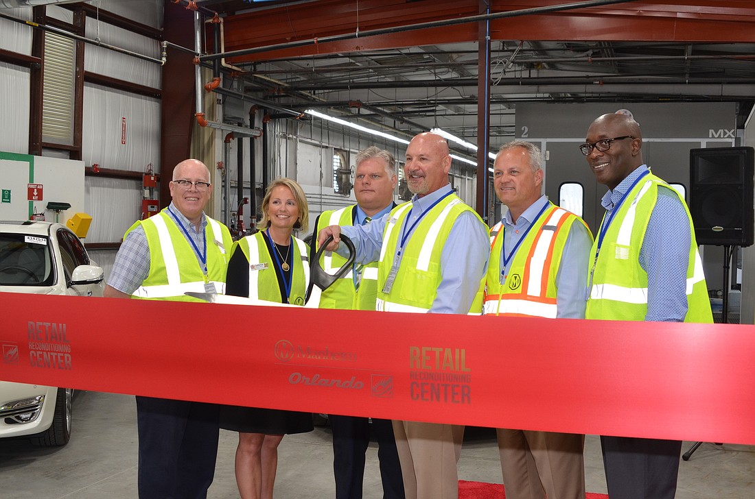 Butch Herdegen, Manheim Orlando Auto Auction general manager, cuts the ribbon to celebrate the opening of the companyâ€™s new 80,000-square-foot vehicle reconditioning center in Ocoee.