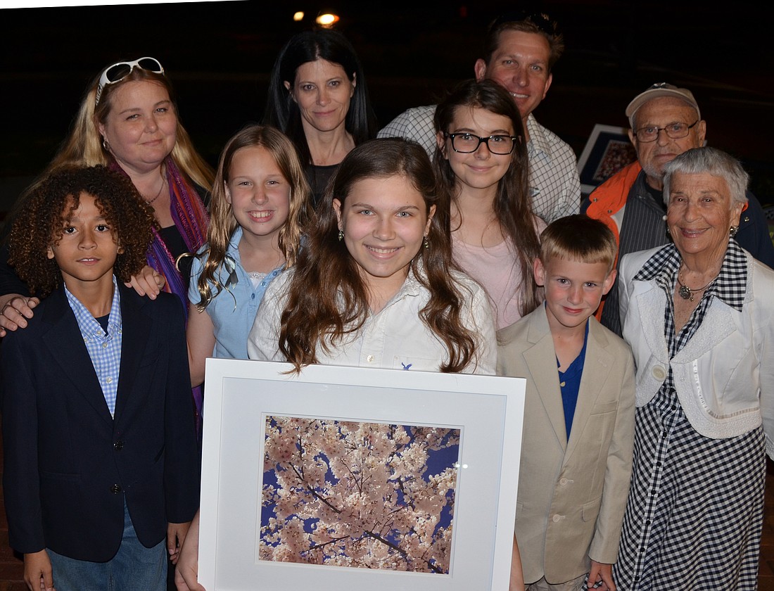 Maia, surrounded by family and friends, holds her favorite photograph.