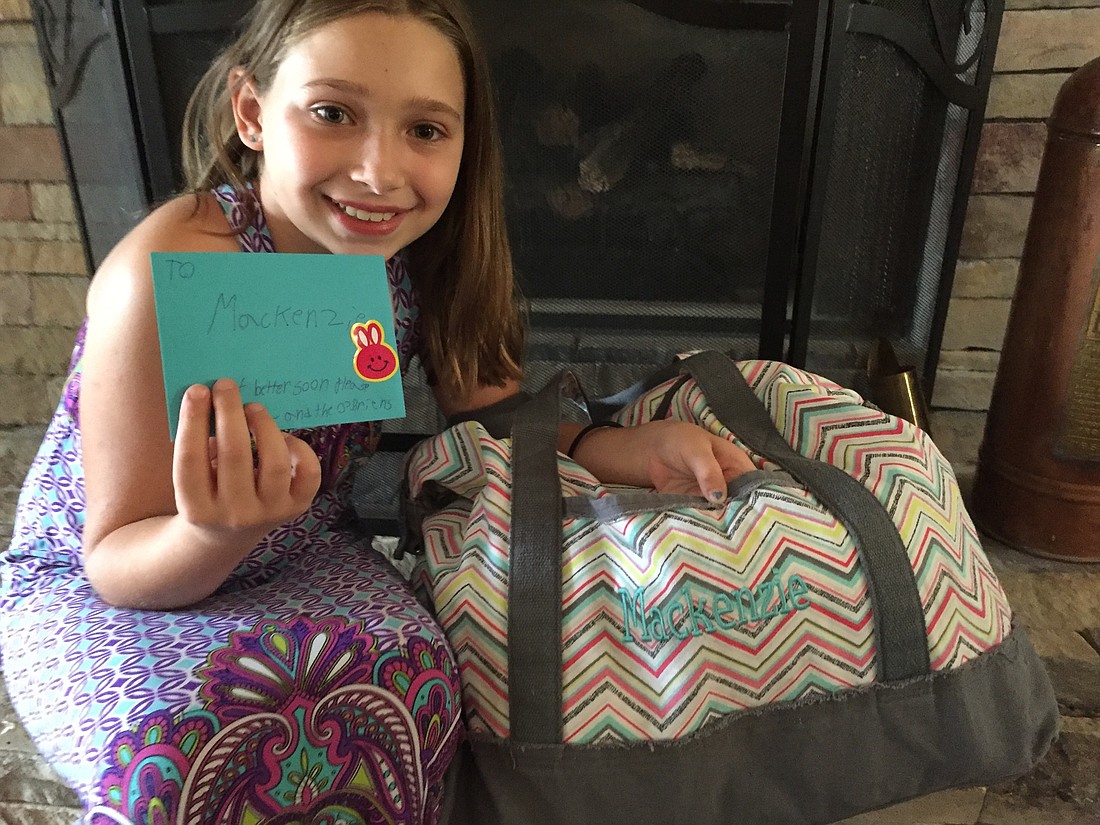Nine-year-old Emily O'Brien, Windermere commissioner Jim O'Brien's daughter, holds a card she wrote for  the young girl who was injured in a plane crash in Lake Down with her father on July 8.