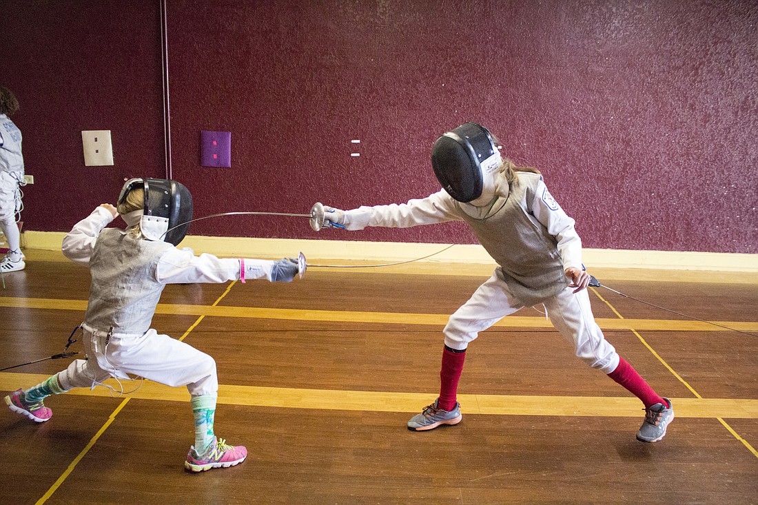 Abby Henne, 10, and Nora Alawwad, 12, practice dueling with foil blades during a fencing class held at Winter Garden Fencing Academy on Monday, July 12.