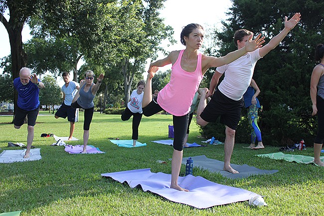 Photo by: Sarah Wilson - Chiropractor Crystal Nix, in pink, participates in the Yoga for a Purpose class in Central Park that she and her husband started to raise money for charity, and support health in the community.