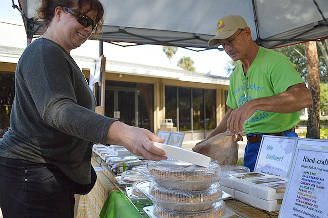 Photo by Paige Wilson - Bud Gray, right, serves up some of wife Tina's homemade pies at the Maitland Farmers Market.