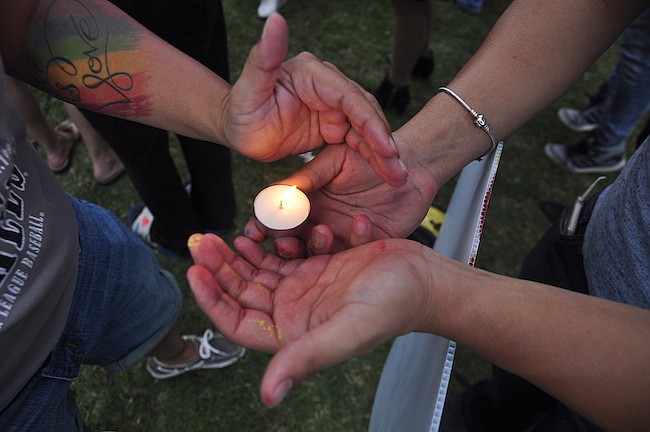Photo by: Isaac Babcock - Mourners light a candle at part of a vigil Monday night in Orlando.