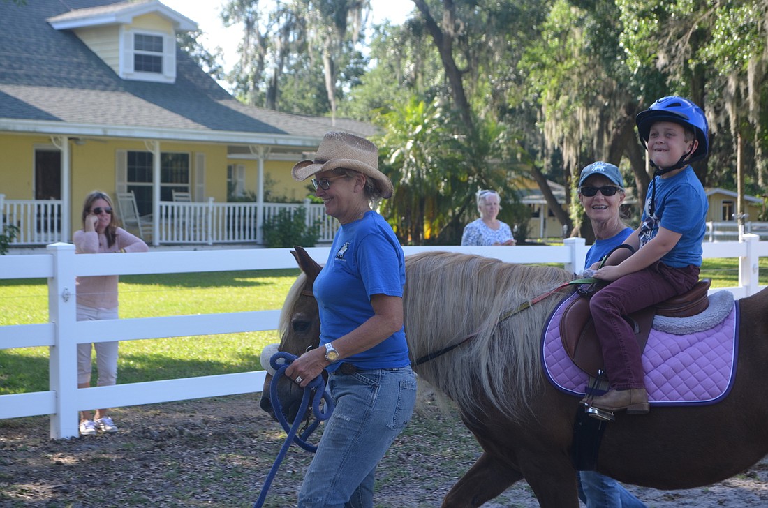 Cooper Vollmer, a six-year-old, participates in riding therapy on his horse, Carly.