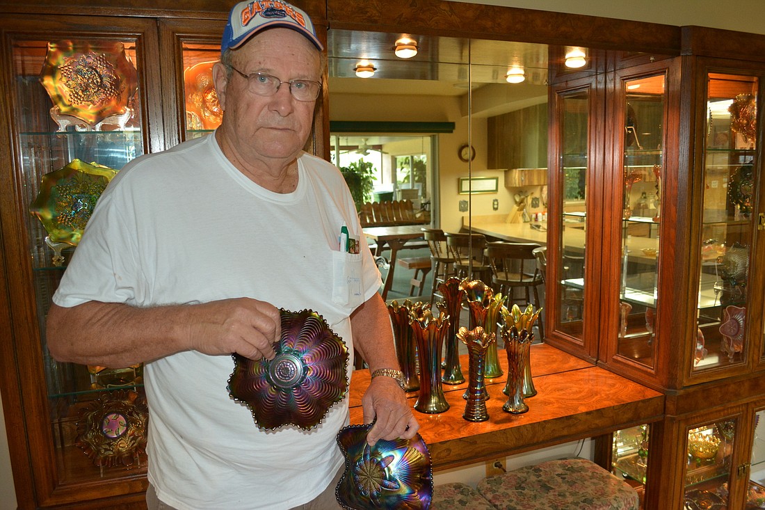 J.R. Leach of Palm Aire removes a pair of carnival glass bowls from his display case at home. He is the vice-president of the Tampa Bay Carnival Glass Club.