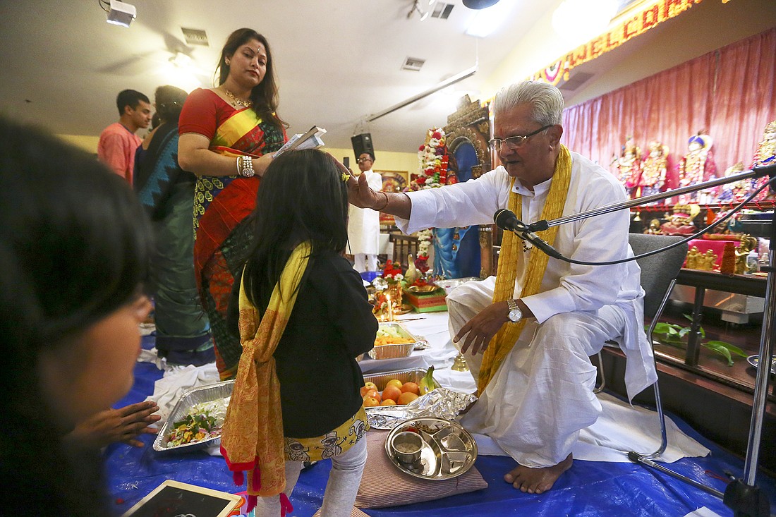 Pandit Batuk Shukla blessed a child during the Saraswati Puja.