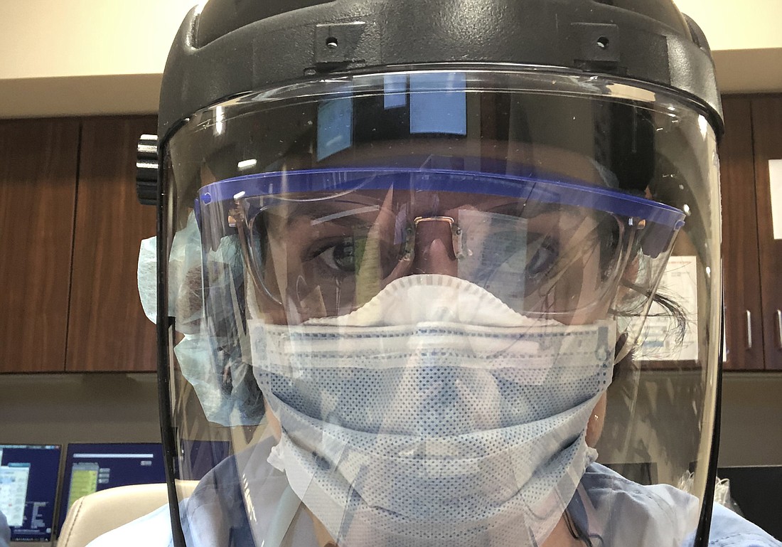 Dr. Charlotte Charfen wears a surgical mask over her N95 mask, protective goggles, gloves, scrubs and even a welding-style face shield to protect herself while treating patients.