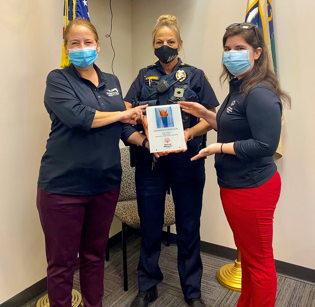 Oakland Police Lt. Angela Campbell, center, received a plaque from representatives of the Lawn Enforcement Torch Run and Special Olympics Florida.