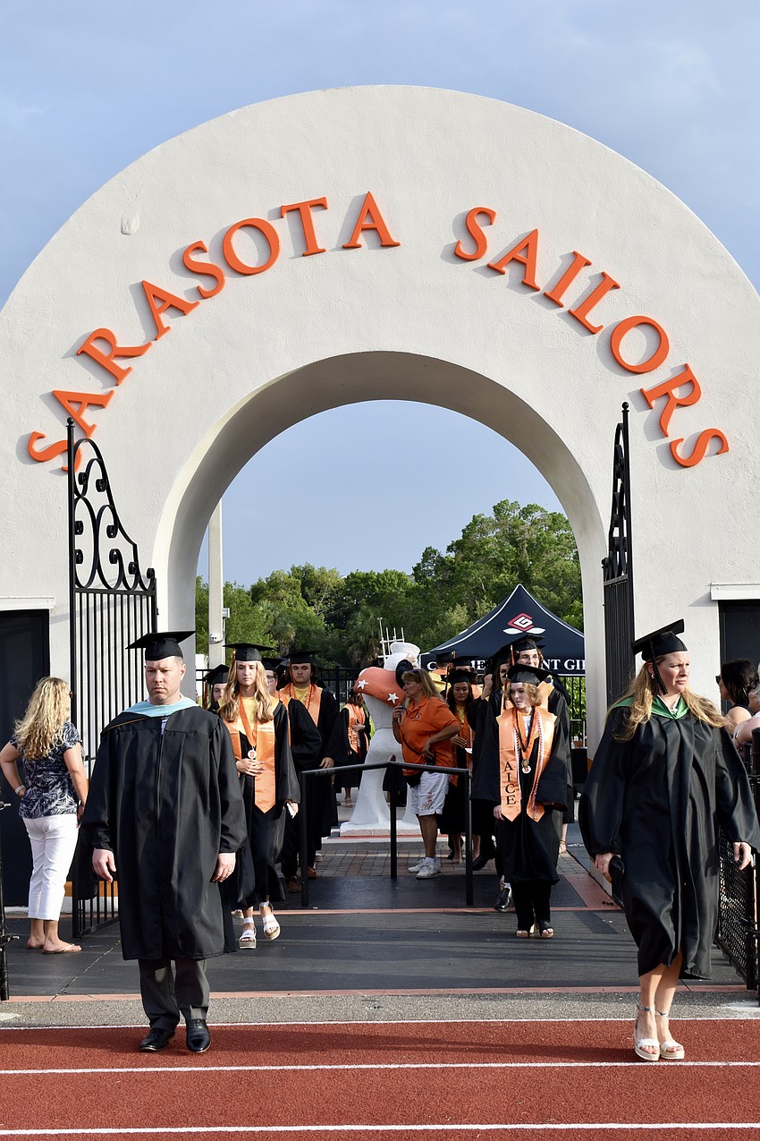 Teachers lead the Class of 2022 through the gates of Cleland Stadium.